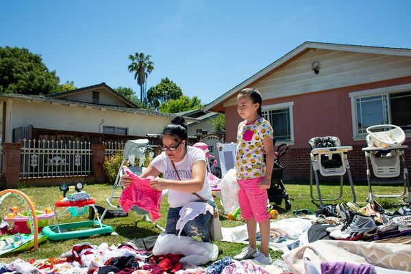 A woman and her daughter look at clothes at a garage sale in the garden of a smaller home. Photo by Laura Morton.