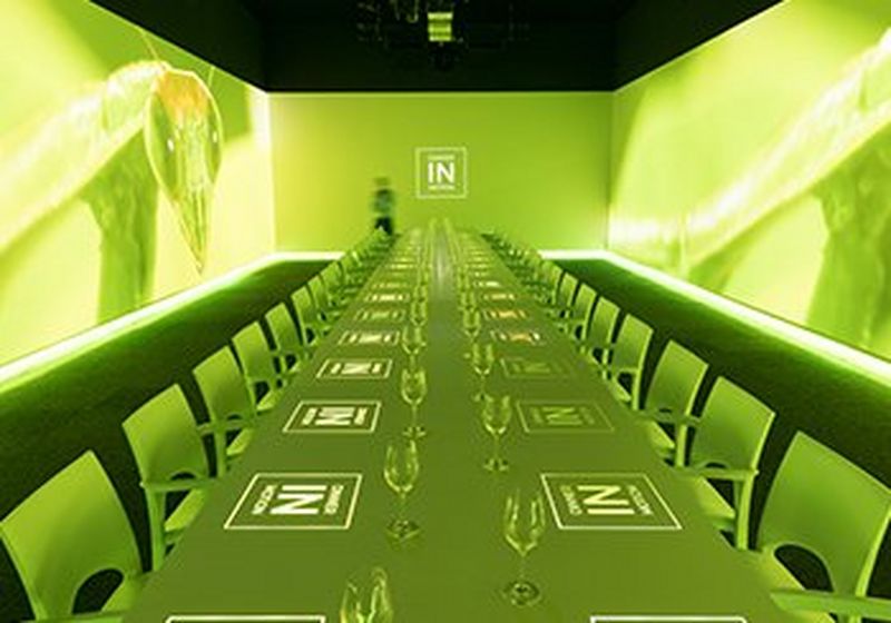 A long dining table, bathed in green light with the Dinner in Motion logos projected onto it.