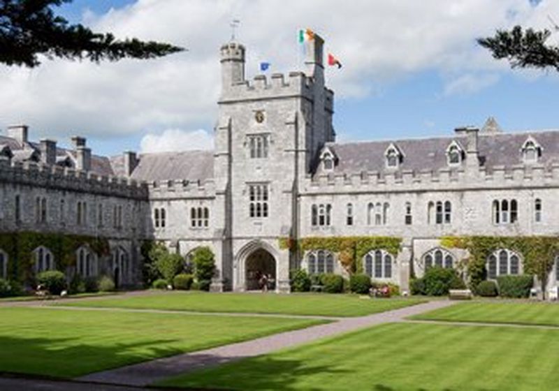 The buildings of University College Cork in Ireland, set against a blue but cloudy sky.