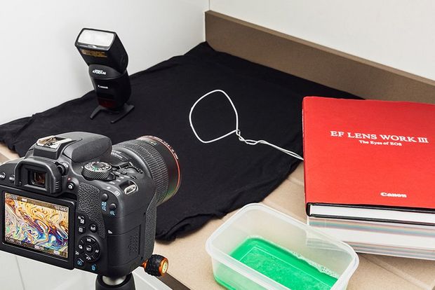 A camera set up to photograph a desk with books on the top. 