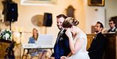 A bride and groom and their guests dancing with their hands raised in the air.