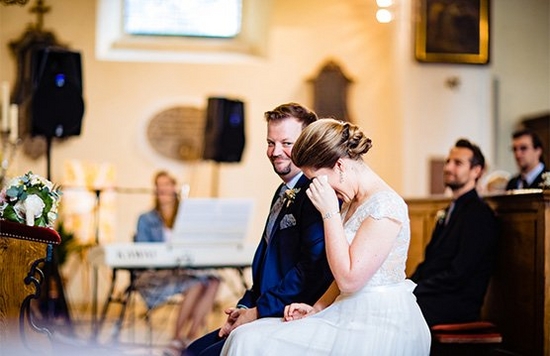 A bride and groom and their guests dancing with their hands raised in the air.