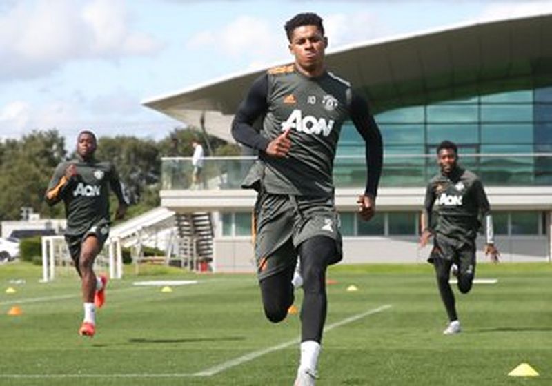 Three young footballers run across the pitch. They are wearing grey strips with AON printed on the front.