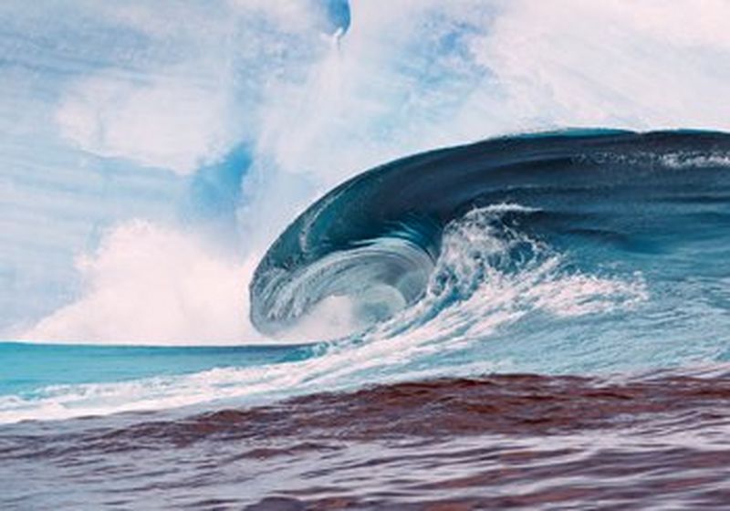 A large wave breaks against a background of an iceberg.