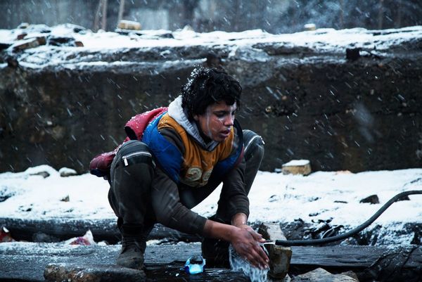 A young Afghan boy washes himself in the only running water available outside an illegal squat in Serbia.