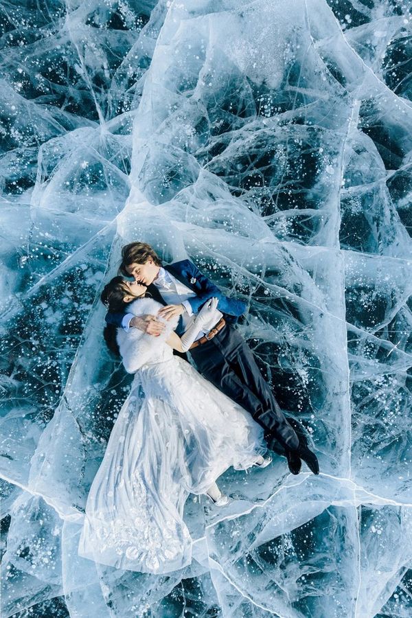 A married couple lie in their finery on a frozen, cracked lake in Russia.