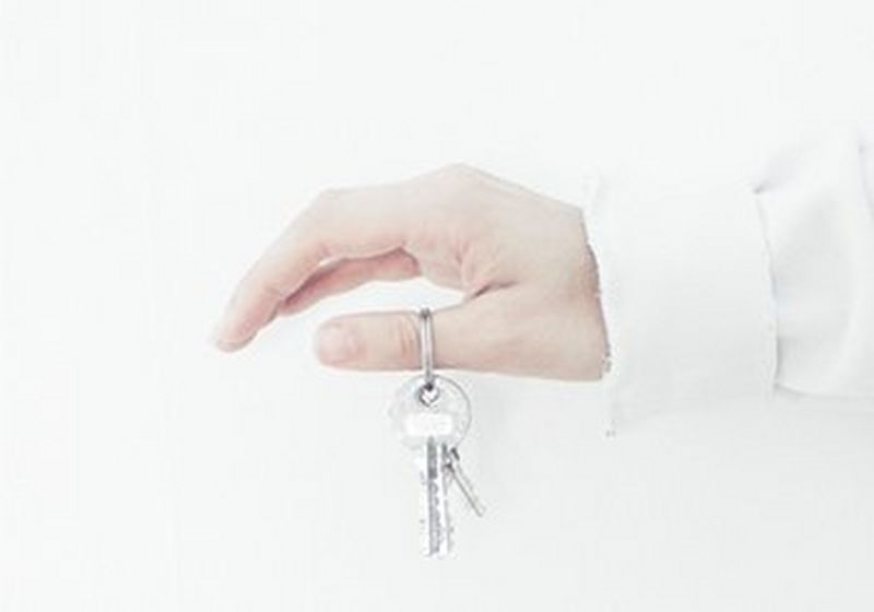 An outstretched arm and hand, dangling a set of keys from the thumb.