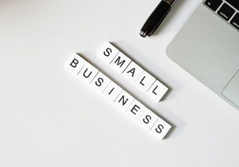 'SMALL BUSINESS' spelled out in tiles on a desk next to a keyboard and pen.