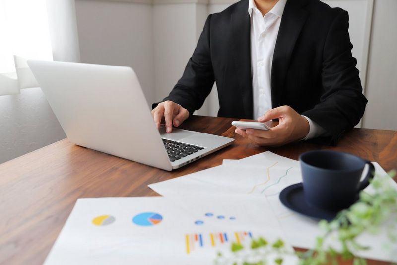 a person looking at their phone and computer