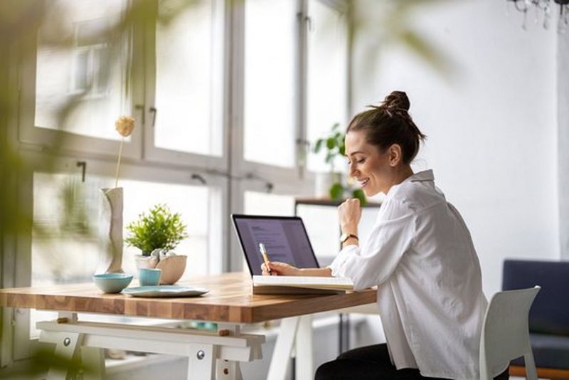 Working professional smiling while writing in her dairy.