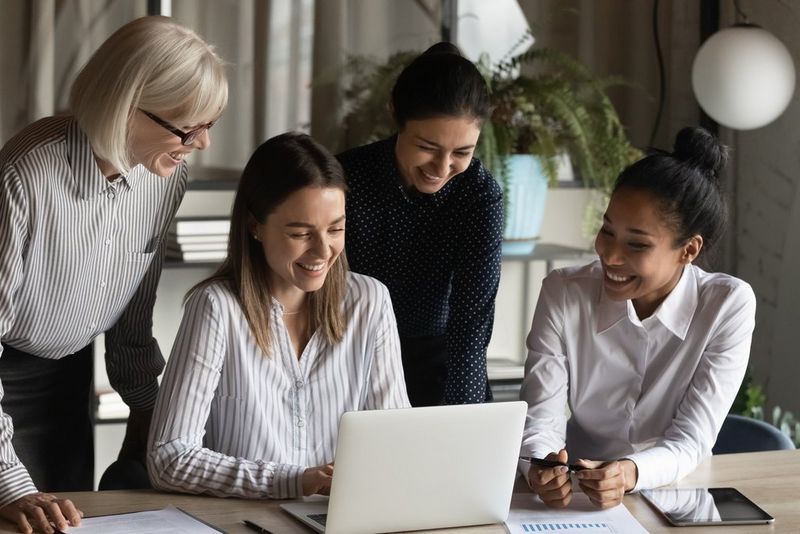 Working professionals smiling and looking at a laptop