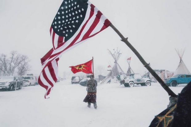 Veterans carry an American and a Mohawk Warrior Society flag through the storm.