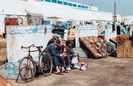 Fishermen in Essaouira, Morocco, sit by the harbour. Photo by Along Dusty Roads.