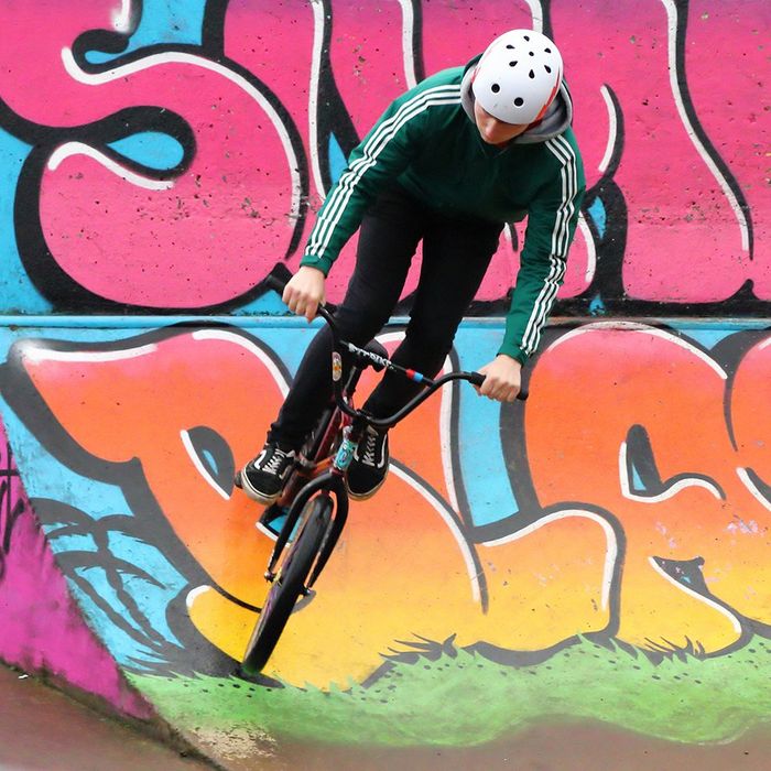 A BMX cyclist performs tricks on a bike ramp with bright graffiti on.