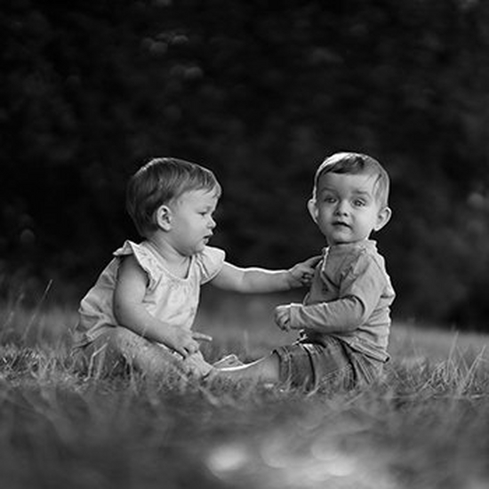 Two children sit on grass.