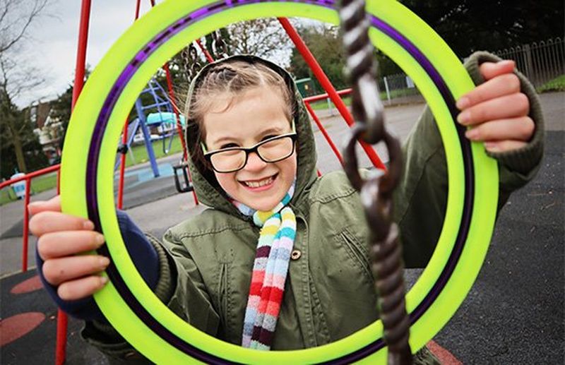 A girl playing in a park holds a yellow frisbee in front of her, framing her face. Taken on a Canon EOS M50 by Katja Gaskell.