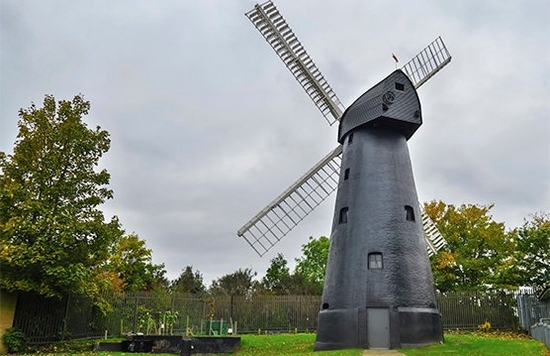 A windmill against a green countryside background on a cloudy day.