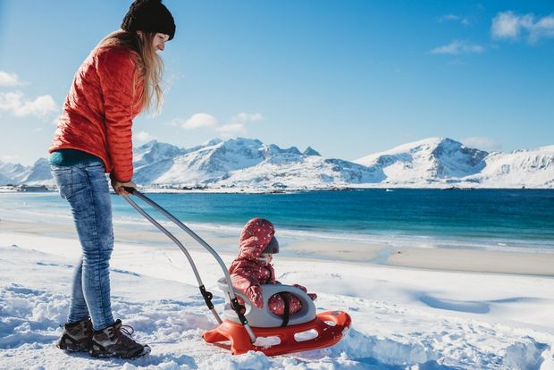 A woman pushes a child on a sled on the Lofoten Islands in Norway.