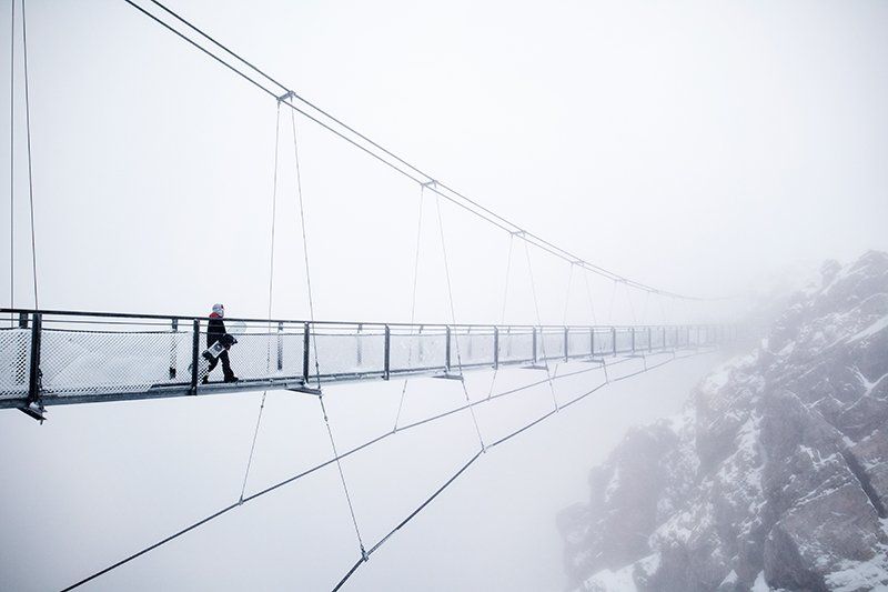 Olympic snowboarding champion Anna Gasser walking on a suspension bridge in fog.