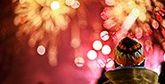 A child watches a burst of gold and pink fireworks.