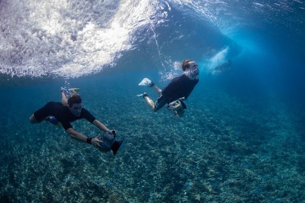 Photographer Ben Thouard and a colleague swimming underwater with cameras in waterproof housings.