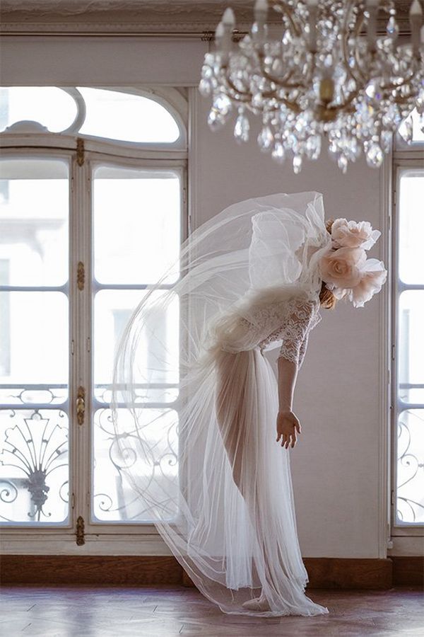 A bride stands in a room and flicks her skirt up above her head. Photo by Félicia Sisco with a Canon RF 85mm F1.2L USM lens.