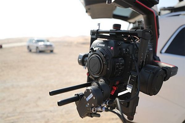 A close-up of the Canon EOS C700 FF mounted on the end of a crane arm attached to a film car.