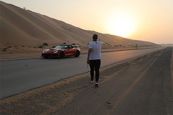 DOP Brett Danton walks towards the orange supercar in the desert at sunset.