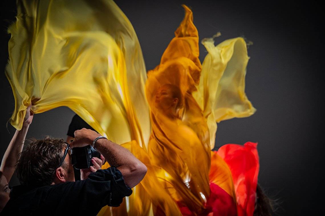 Clive Booth fotografiert einen Tänzer, der in orangene und gelbe Seide eingehüllt ist.