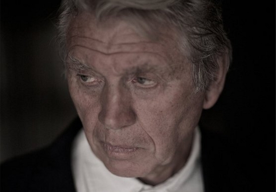 Sir Don McCullin, dressed in a white shirt and black jacket, poses for a portrait shot. 