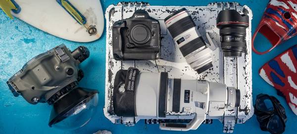 A Canon EOS-1D X Mark III and lenses on a well-used hard case with an underwater camera housing, flippers and other kit.