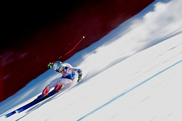 A skier performing a turn on a steep downhill run.