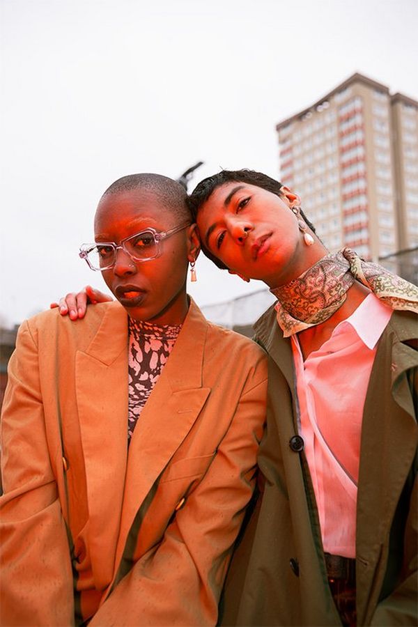 A male and female model pose outside a block of flats, an orange glow on them. Photo by Rianna Gayle on a Canon EOS-1D X Mark II.