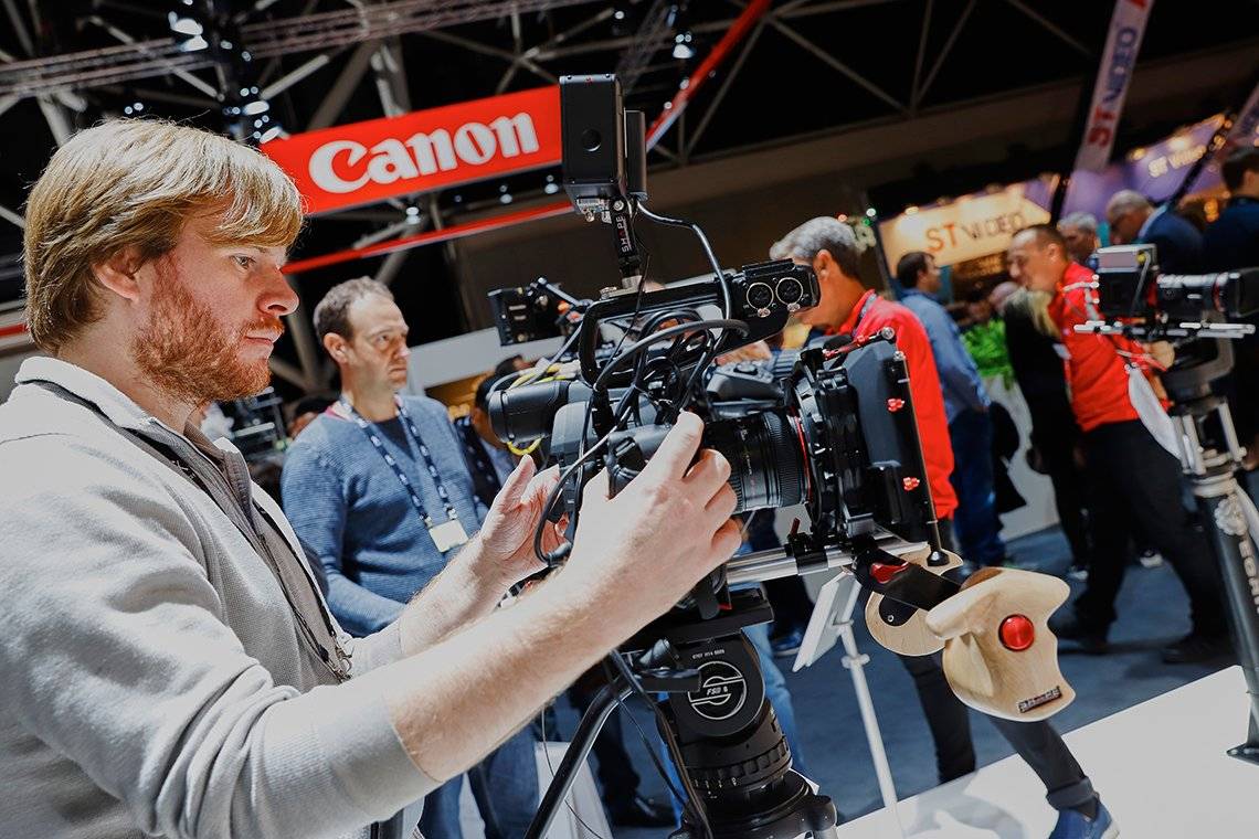 A man operates a Canon video camera on the Canon stand at IBC 2017.
