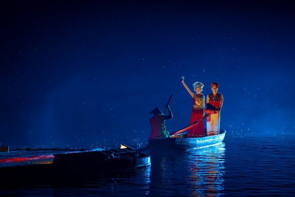 At night, a man and a woman stand on a boat in the River Li. The woman's arm is raised. Taken by Joel Santos on a Canon EOS 5D Mark IV.