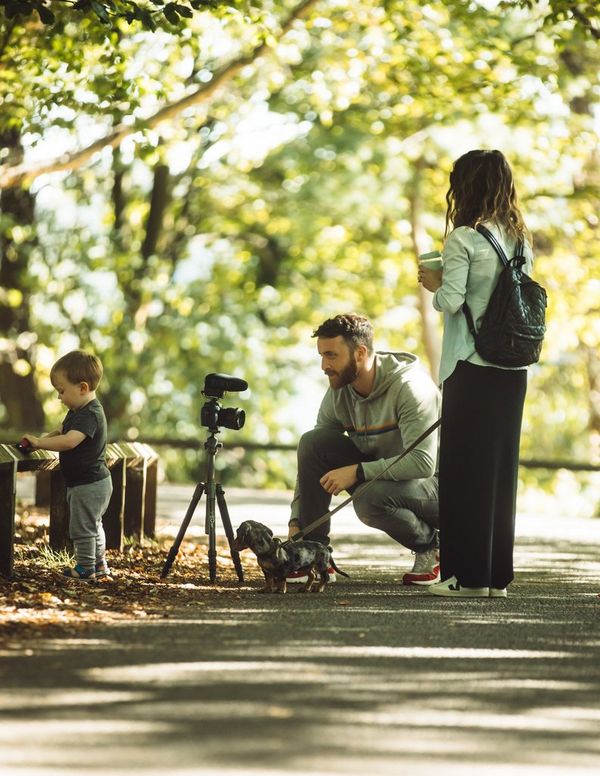 The Michalaks filming on a path in the park with their dog. 