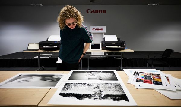 Helen Bartlett inspecting her A2 prints laid out on a table. 