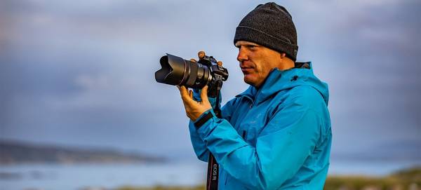 Richard Walch holds the Canon EOS R system on location by the sea. 