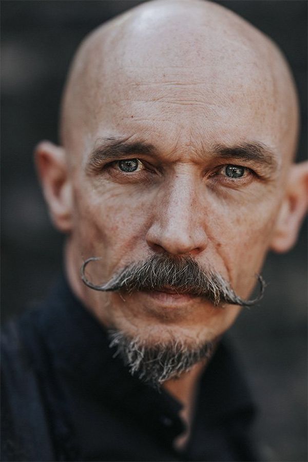 A close-up of a bald man with a styled, curled moustache. Photo by Rosie Hardy with a Canon RF 85mm F1.2L USM lens.