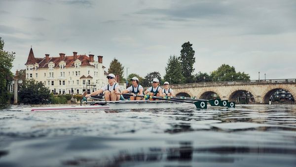An image taken from the water level showing the rowers in action as they head underneath a bridge. 