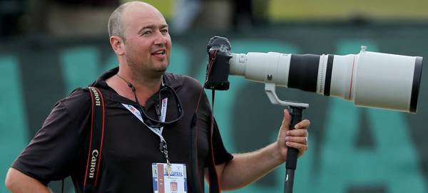 Getty Images sports photographer Warren Little standing in a stadium with his Canon camera and a long lens. © Getty Images