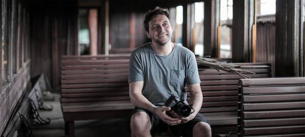 Photographer Samo Vidic is pictured in a train carriage, holding his Canon EOS 5D Mark IV. 