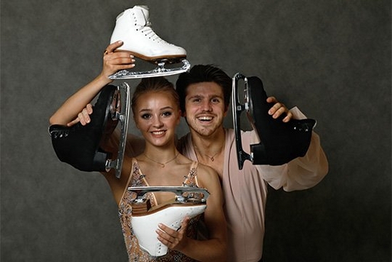 A male and female ice skater holding their ice skating boots. Photograph by Andrey Golovanov.