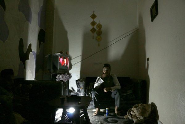A project participant's image, showing a man sitting in semi-darkness watching television, to illustrate the boredom experienced within the camp. 