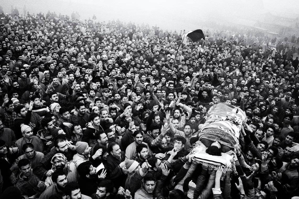 Kashmiri mourners shout slogans and wave the Pakistani flag while carrying the dead body of a militant.