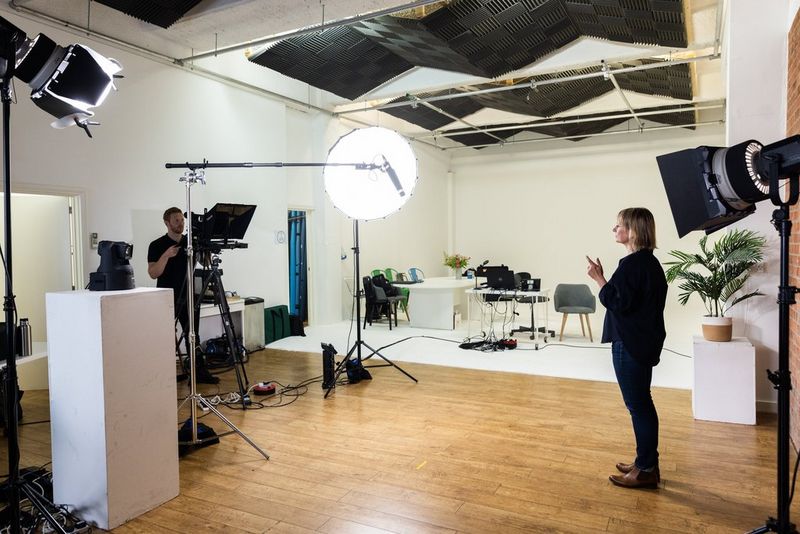 An unmanned Canon CR-N700 and a manned Canon XF605 both point at a woman standing on a set. 