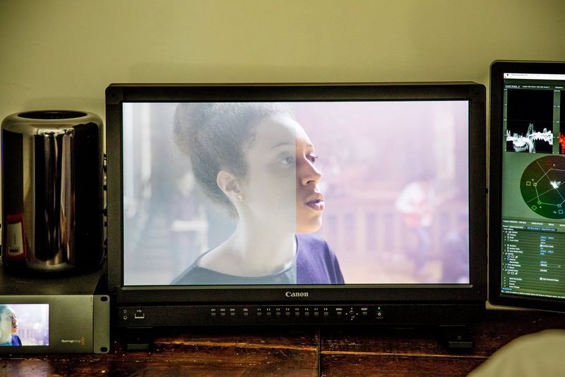 A frame of a woman on a monitor, with the left half of the frame low in contrast and saturation but the right half clearer and brighter.