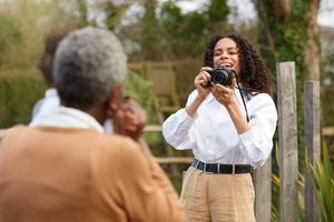 Osoba drži fotoaparat EOS R100 tvrtke Canon kako bi fotografirala dva člana obitelji prikazana odostraga.