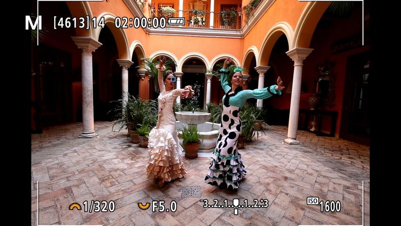 Two flamenco dancers in a courtyard, seen in the display of a Canon EOS R10 with various settings visible.