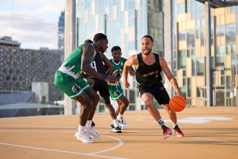 Four basketball players in action on a court, one captured dribbling the ball with the ball in mid-air. Shot on Canon EOS R1.